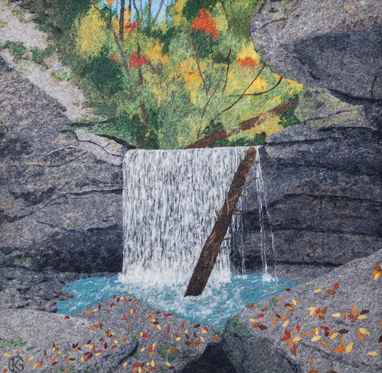 A two-dimensional felted wool landscape of a waterfall in the forest.