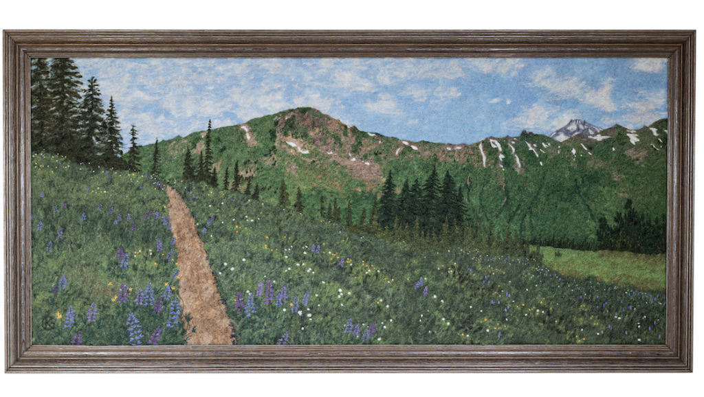A framed, two-dimensional felted landscape of a mountain ridge in the Northern Cascades and a meadow with lots of blooming lupines.